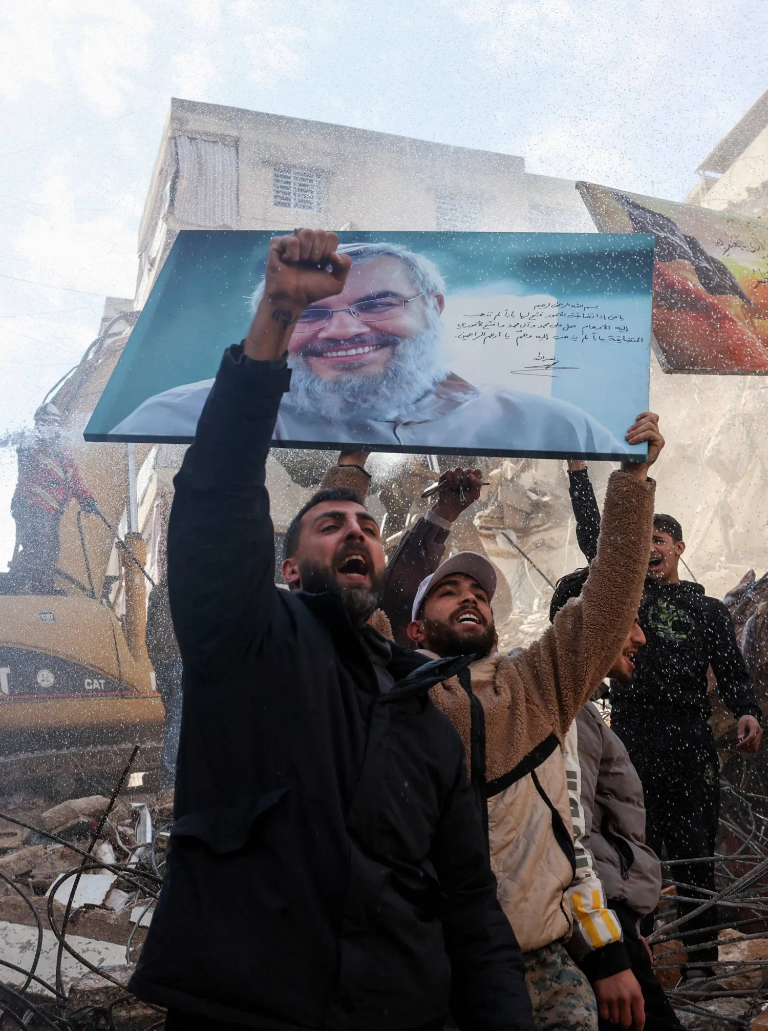 مناصرون لـ«حزب الله» يرفعون صورة لأمين عام الحزب السابق حسن نصر الله في الضاحية الجنوبية لبيروت حيث الدمار يعم المكان (رويترز)