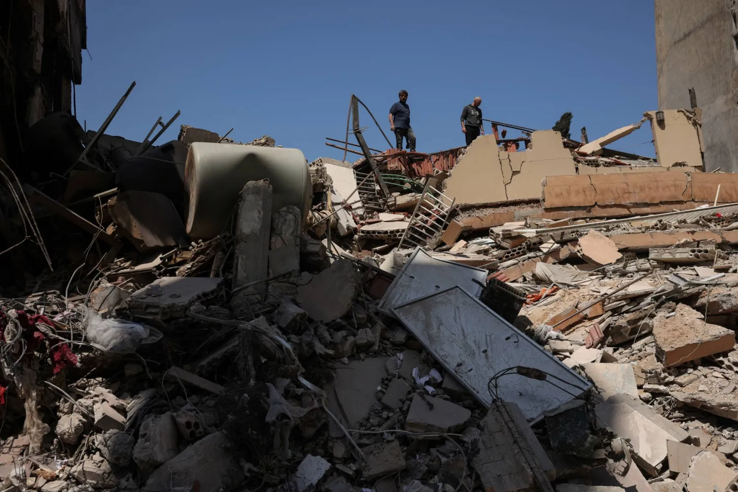 مواطنون يعاينون مبنى تم قصفه بغارة إسرائيلية في منطقة صور بجنوب لبنان (رويترز)