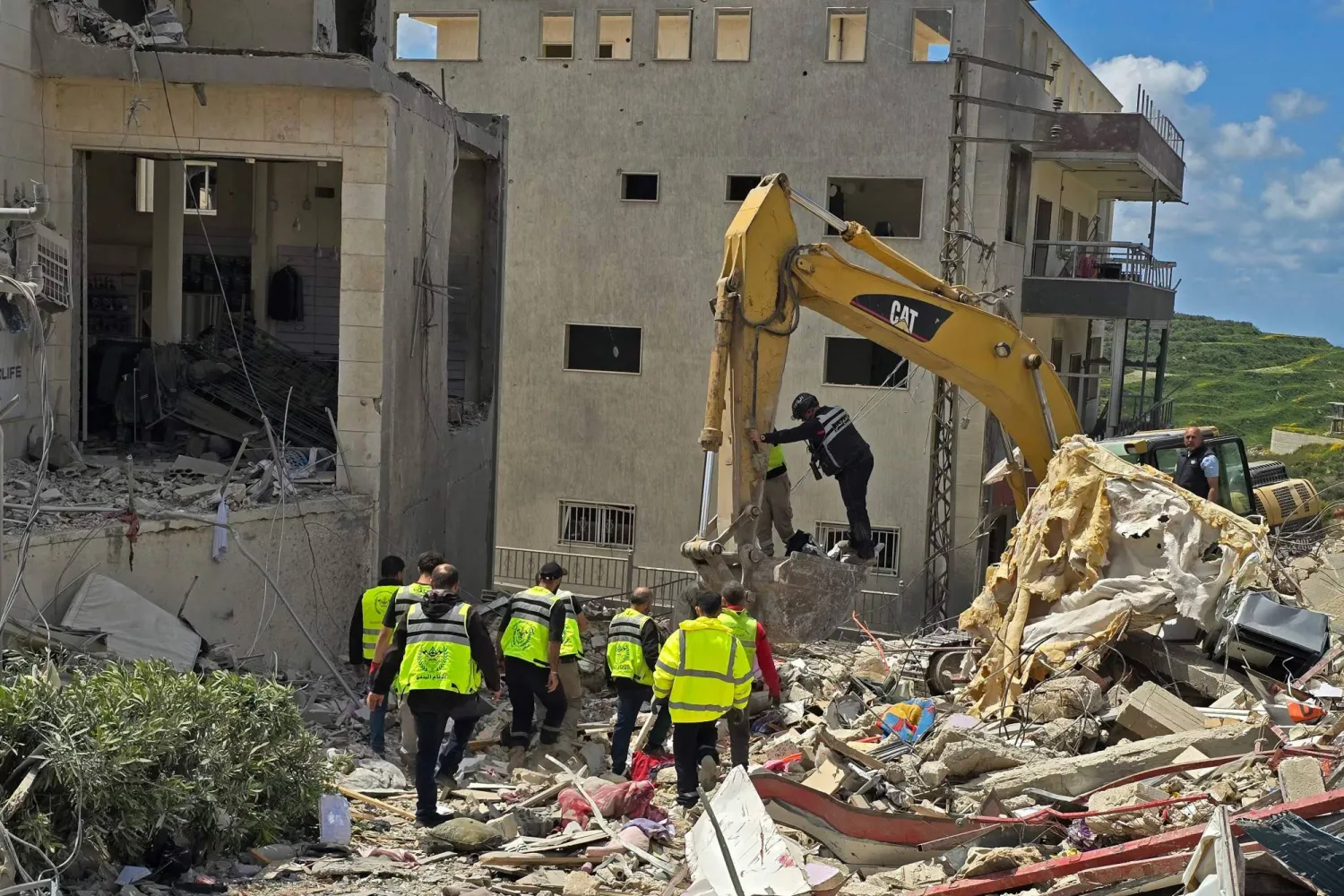 عناصر الدفاع المدني يبحثون عن القتلى والجرحى تحت أنقاض مبنى استهدف في بلدة قانا في جنوب لبنان ما أدى إلى سقوط قتلى وجرحى (أ.ف.ب)