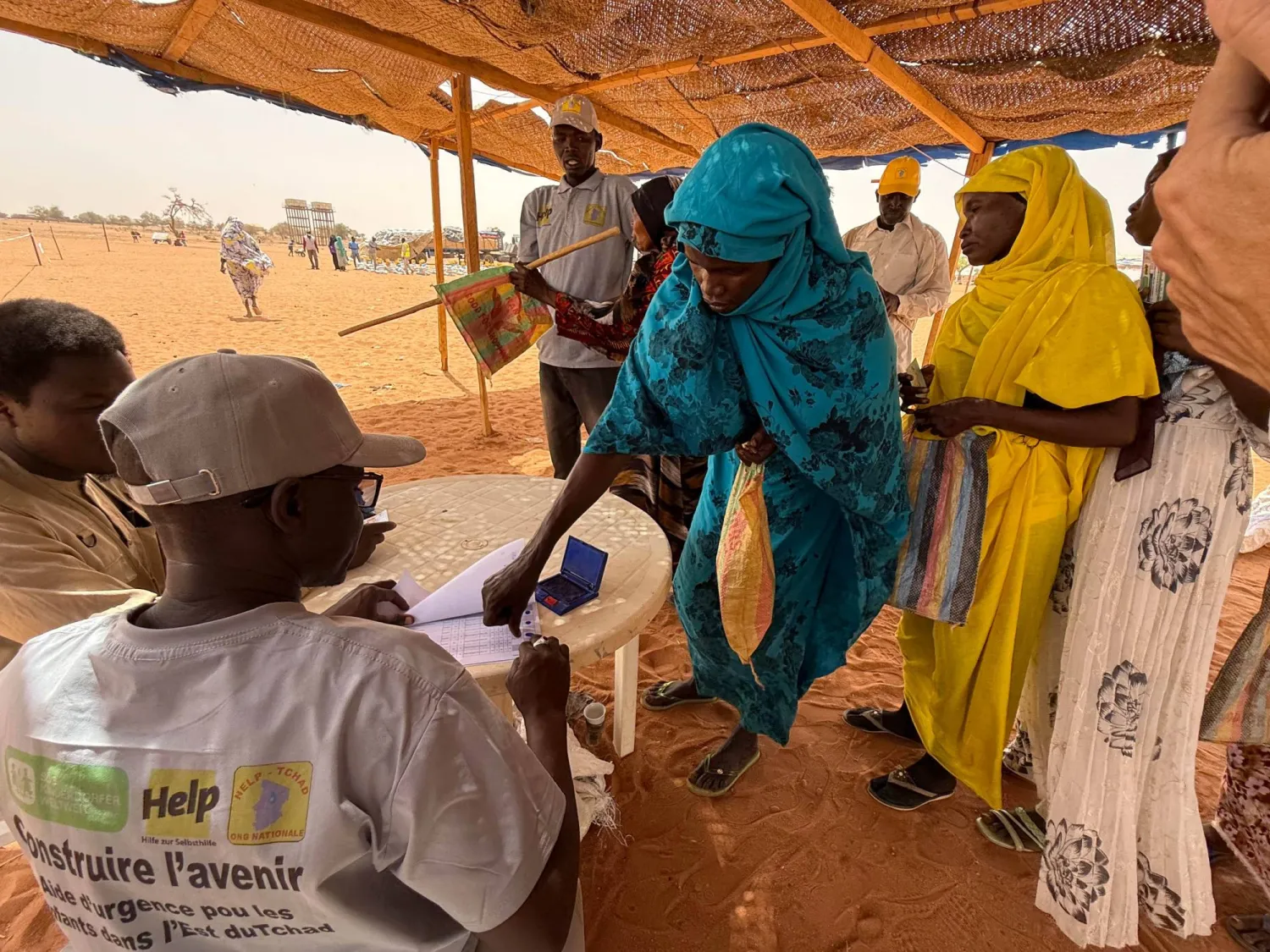 09 April 2026, Chad, Aboutengye: Sudanese refugee women at the Aboutengue refugee camp in eastern Chad present a voucher and provide a fingerprint to confirm receipt before receiving their food rations. Photo: Eva Krafczyk/dpa
