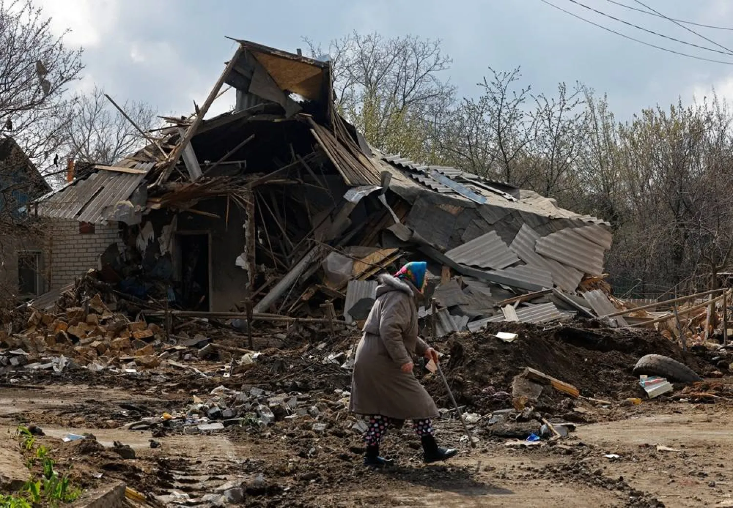 An elderly woman walks past the ruins of a house, which was destroyed during what Russian-installed authorities called a Ukrainian overnight drone attack, in the course of Russia-Ukraine conflict in Yasynuvata (Yasinovataya) in the Donetsk region, a Russian-controlled area of Ukraine, April 11, 2026. (Reuters)