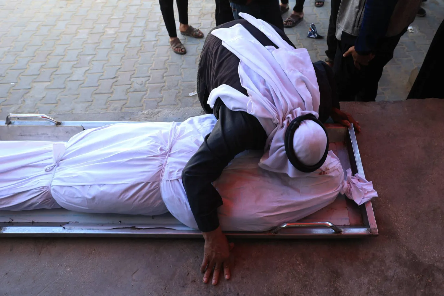 A Palestinian man kisses a shrouded body during the funeral of Palestinians who, according to a medic, were killed the night before in an Israeli strike at al-Aqsa Martyrs Hospital in Deir al Balah in the central Gaza Strip on April 13, 2026. (Photo by Eyad Baba / AFP)
