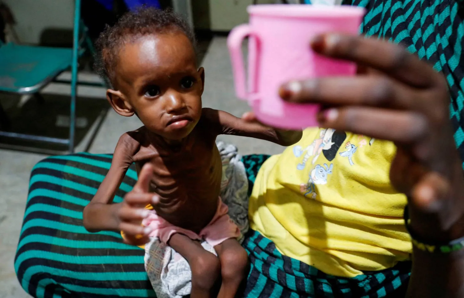 Saddam Najwa, a malnourished, 17-month-old internally displaced child reaches out for a cup of water at the paediatric ward of the Mother of Mercy Hospital in Gidel, near Kauda, within the Sudan's People Liberation Movement-North (SPLM-N) controlled area of the Nuba Mountains, South Kordofan, Sudan June 25, 2024. REUTERS/Thomas Mukoya/File Photo