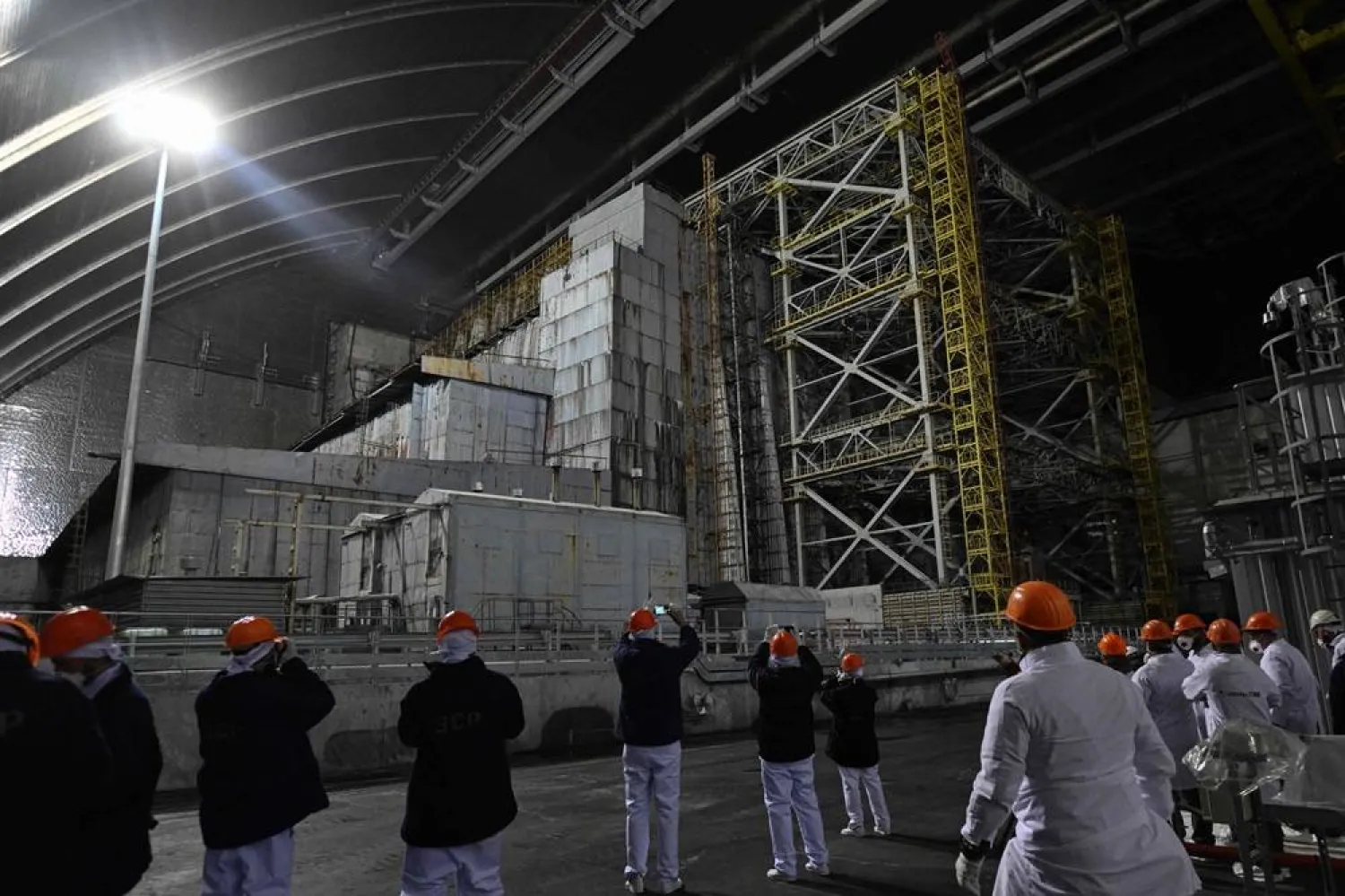 Representatives of Greenpeace and media stand in front of the sarcophagus covering the destroyed fourth reactor under the New Safe Confinement (NSC), at the Chernobyl Nuclear Power Plant on April 9, 2026. (AFP)