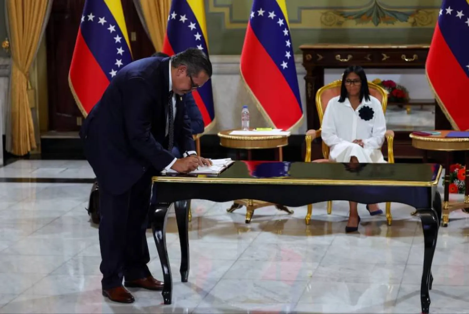 الرئيسة المؤقتة لفنزويلا ديلسي رودريغيز تتابع في حين يوقع رئيس «شيفرون» في فنزويلا على اتفاقية نفطية مع شركة النفط الحكومية الفنزويلية «PDVSA» في كاراكاس 13 أبريل 2026 (رويترز)