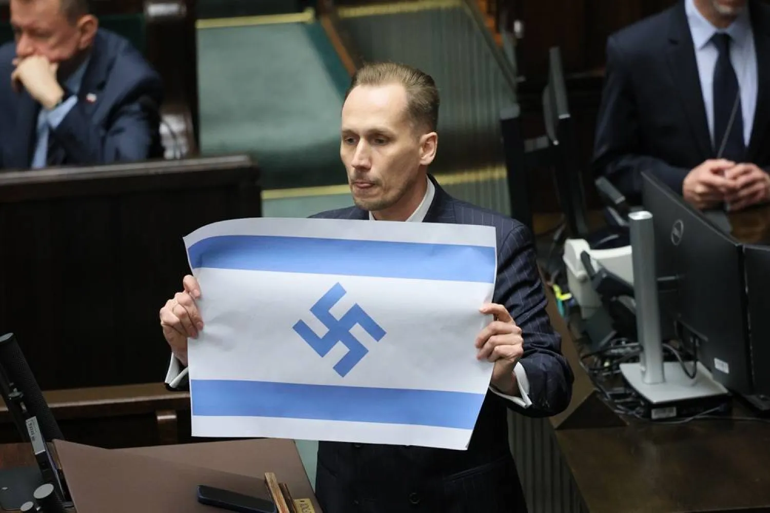 Polish Far-right Confederation party MP Konrad Berkowicz dsiplays an Israeli flag marked with a swastika in the Sejm in Warsaw, Poland, 14 April 2026. (EPA)