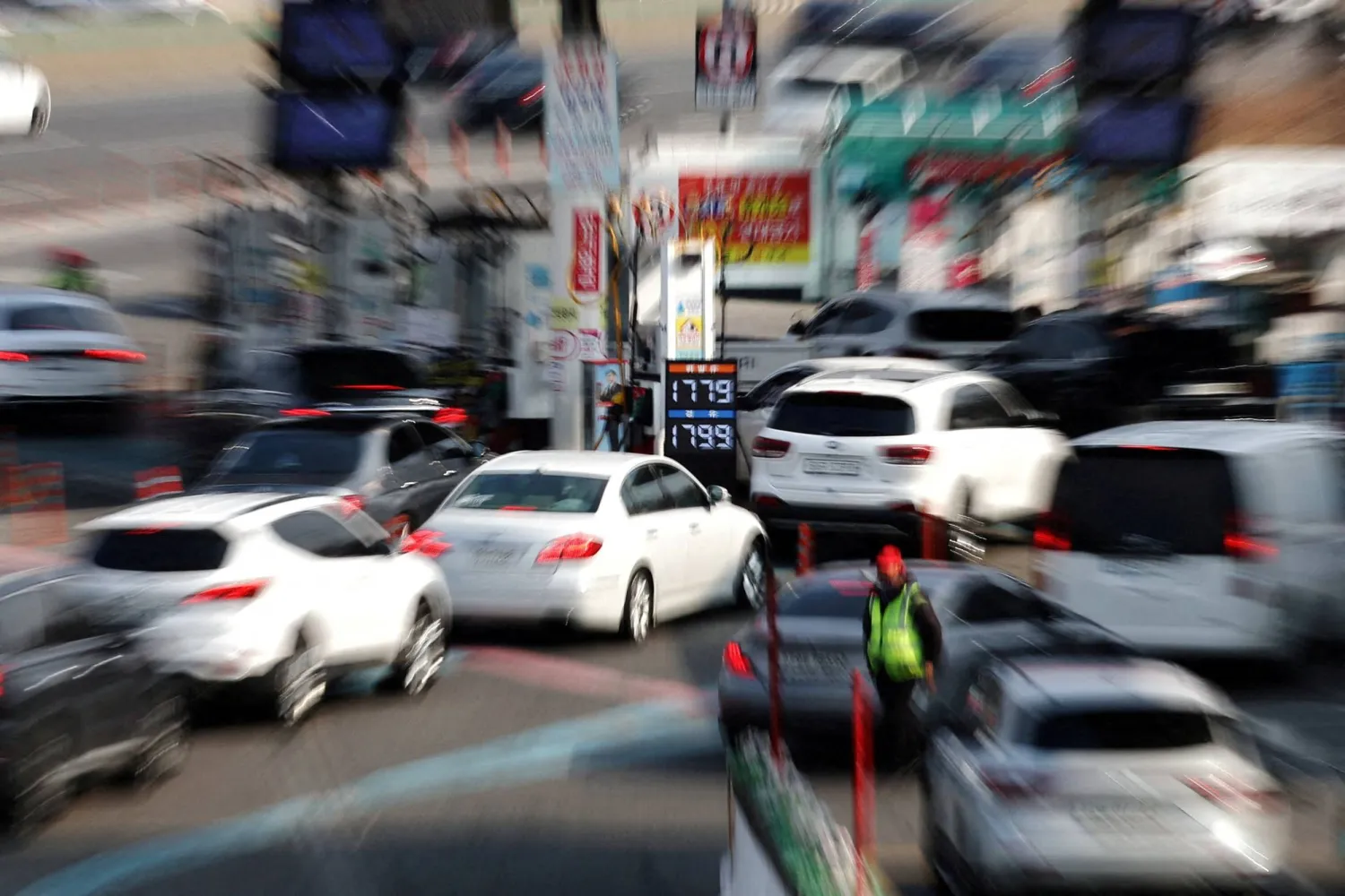 A display shows oil prices as cars queue at a gas station in Seoul. (Reuters)