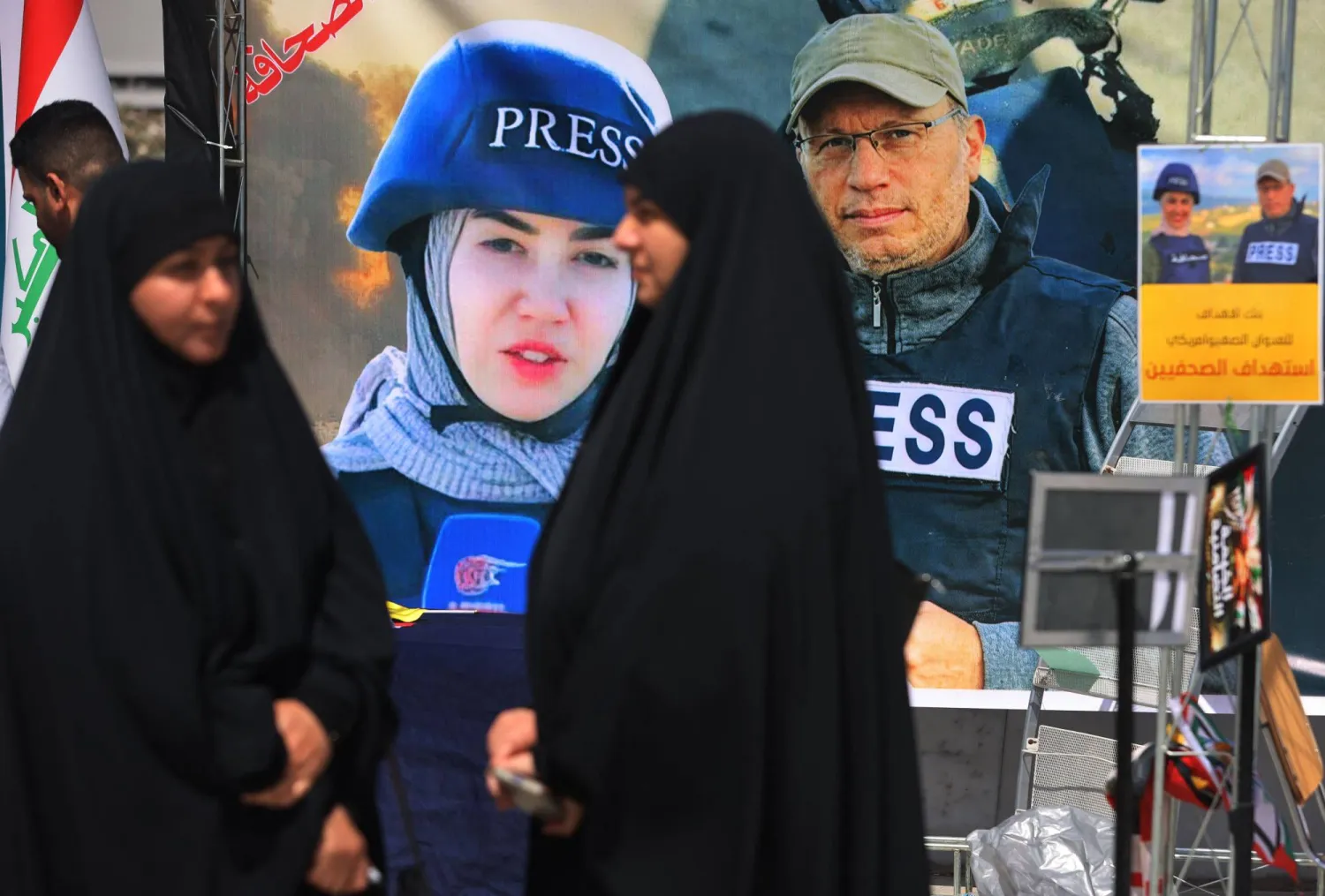 أشخاص يمرون أمام لافتة تعرض صور الصحافييَن فاطمة فتوني وعلي شعيب اللذين قُتلا في غارة إسرائيلية في جنوب لبنان خلال مظاهرة في بغداد 7 أبريل 2026 (أ.ف.ب)