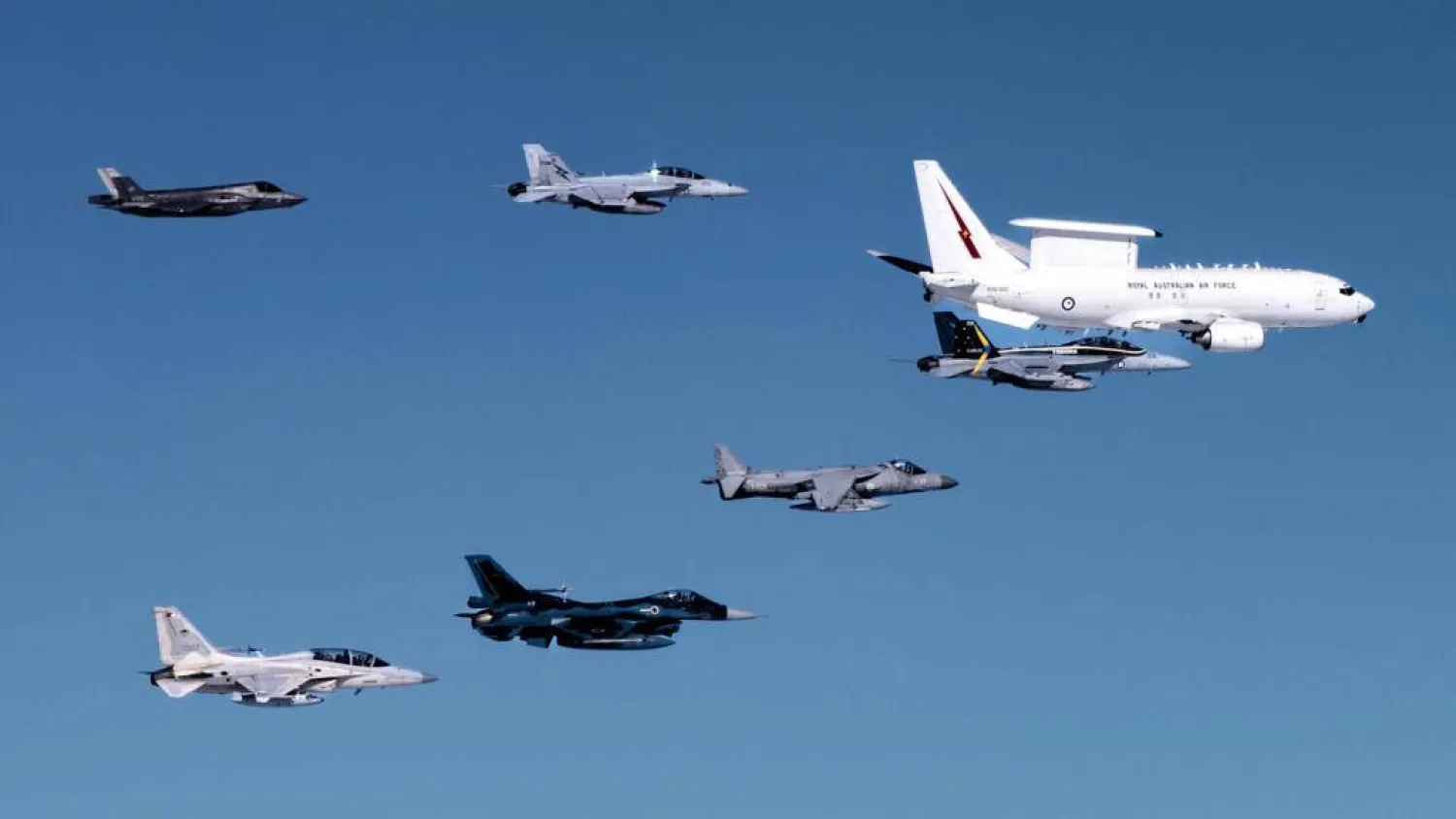  This handout image taken on July 23, 2024 and released by the Australian Defense Force shows a Royal Australian Air Force (RAAF) E-7A Wedgetail airborne early warning and control aircraft (top R) in formation flight with an RAAF EA-18G Growler electronic warfare aircraft (bottom R), RAAF F/A-18F Super Hornet (top C), a Spanish Navy AV-8B Harrier II (bottom C), an F-35 Lightning II (top L), a Japan Air Self-Defense Force Mitsubishi F-2 (bottom 2nd L), and a Philippine Air Force FA-50 Golden Eagle (bottom L) over northern Australia during Exercise Pitch Black 2024.  Handout / AUSTRALIA DEFENCE FORCE/AFP