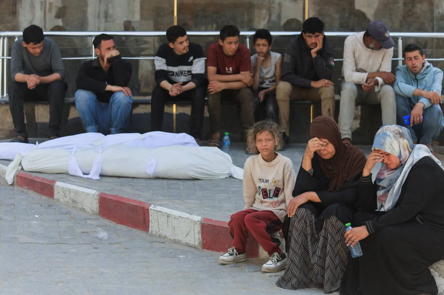 فلسطينيون إلى جوار جثماني الشقيقين عبد الملك وعبد الستار العطار اللذين قُتلا في غارة إسرائيلية قبل تشييعهما في مدينة غزة يوم الخميس (رويترز)