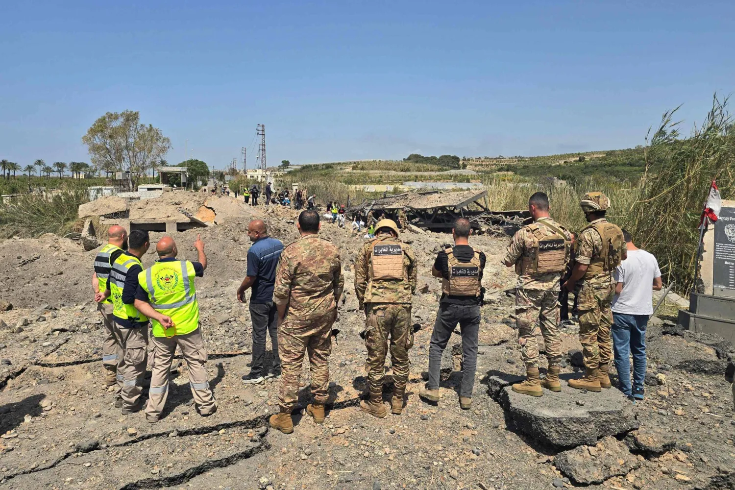 جنود الجيش اللبناني وعناصر الدفاع المدني يتفقدون موقع الغارات الإسرائيلية التي استهدفت جسر القاسمية المبني فوق نهر الليطاني في منطقة القاسمية جنوب لبنان (أ.ف.ب)