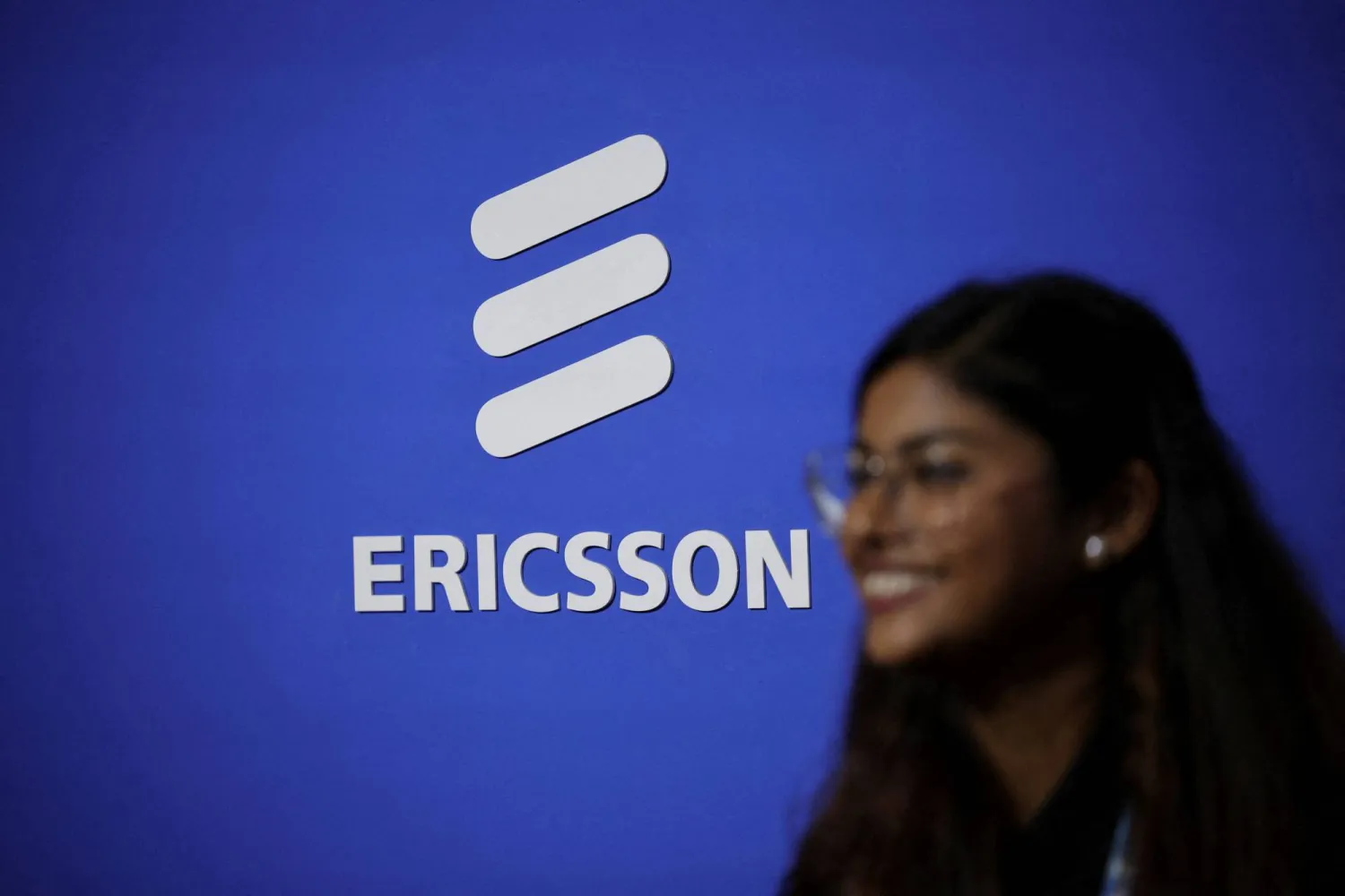 FILE PHOTO: A woman walks across the logo of Ericsson at the ongoing India Mobile Congress 2025 at Yashobhoomi, a convention and expo center in New Delhi, India, October 8, 2025. REUTERS/Anushree Fadnavis/File Photo