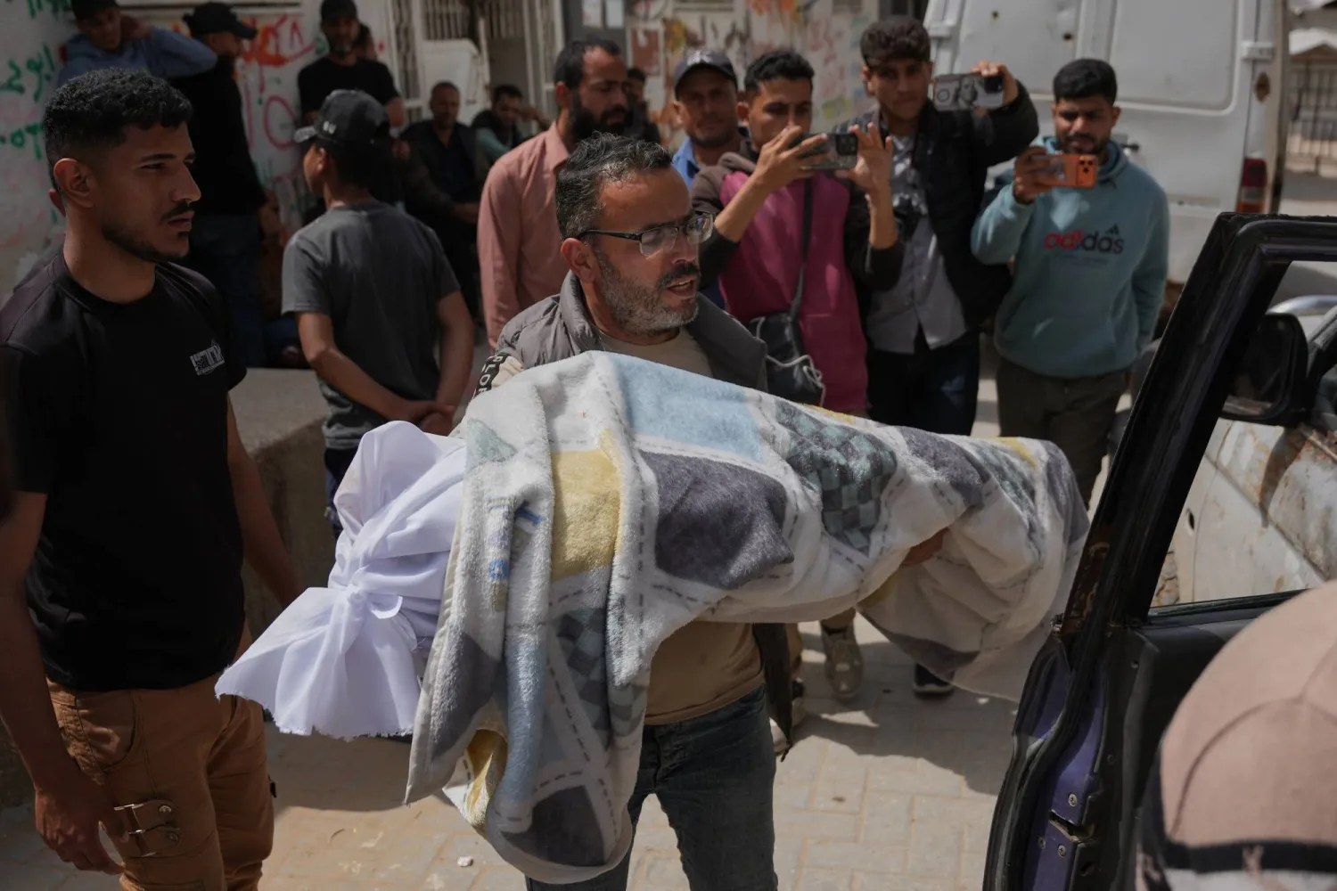 فلسطيني يحمل جثمان فتى (12 عاماً) قُتل برصاص إسرائيلي خلال تشييعه خارج «مستشفى الشفاء» بمدينة غزة الجمعة (أ.ب)