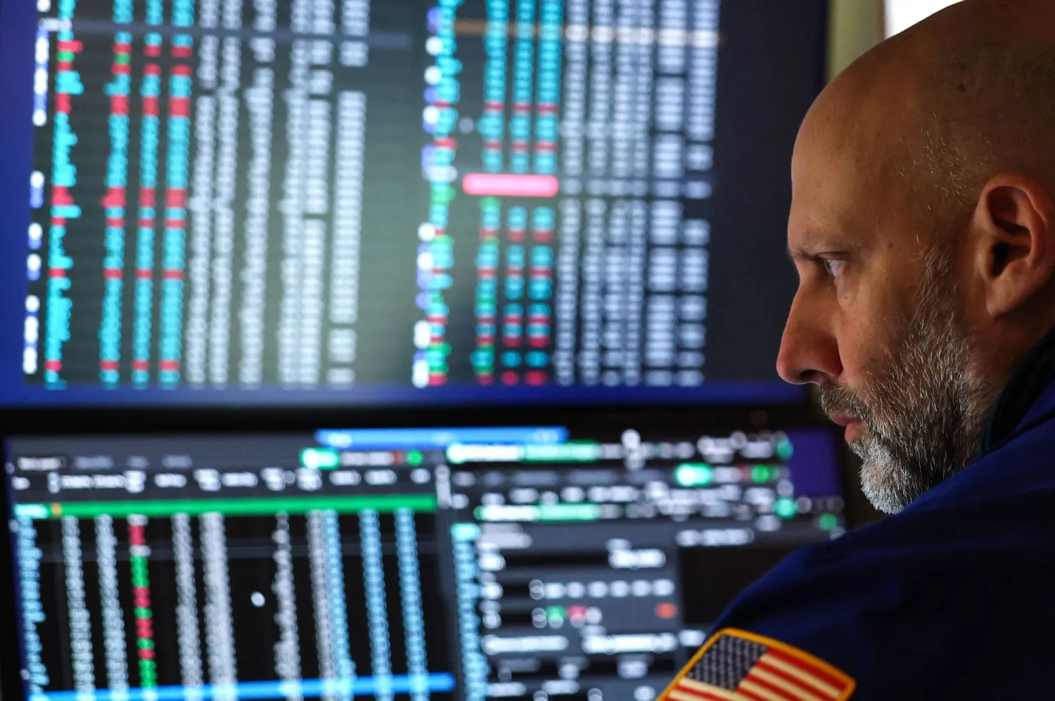 متداول يراقب شاشات تعرض مؤشرات الأسهم في بورصة نيويورك (أ.ف.ب)