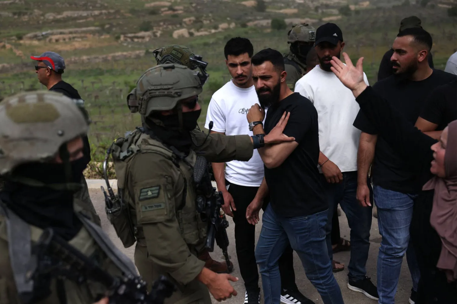 A Palestinian woman (R) reacts as an Israeli soldier pushes a man while Palestinians are forcibly removed as they try to reach their land after Israeli settlers reportedly attacked local farmers working on their fields, spraying them with pepper spray, near the Palestinian village of Halhoul, south of the Israel-occupied West Bank city of Hebron, on April 17, 2026. October 2023. (Photo by HAZEM BADER / AFP)