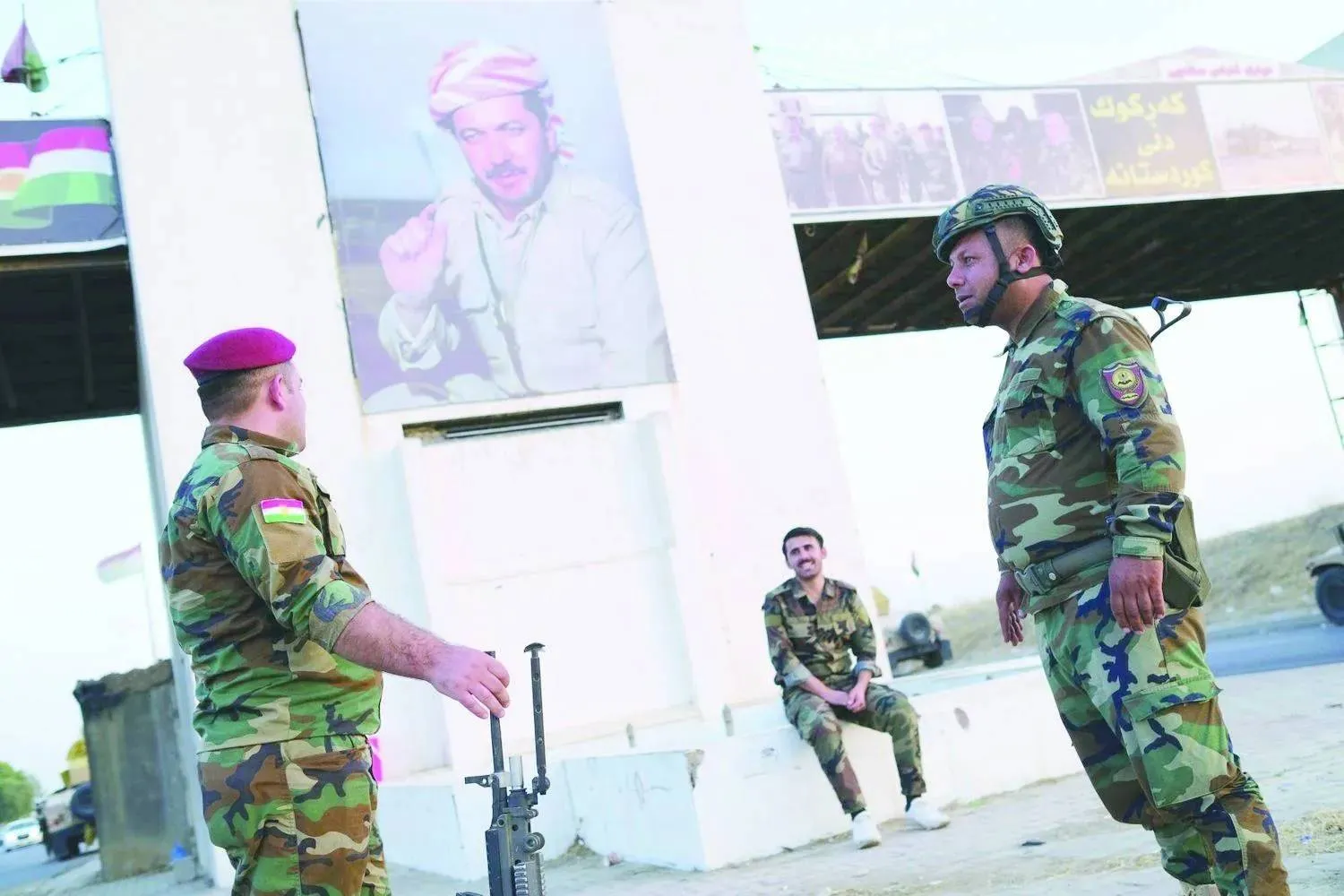 Peshmerga fighters are positioned beneath a portrait of Masoud Barzani in Kirkuk (file photo – EPA)