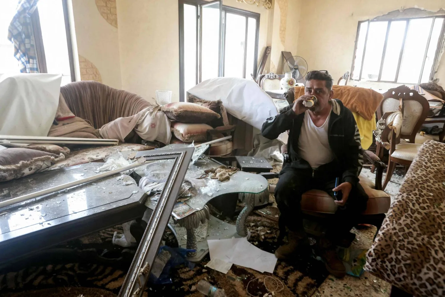 مواطن يشرب الشاي في بيته المتضرر في بلدة قانا في جنوب لبنان (أ.ف.ب)