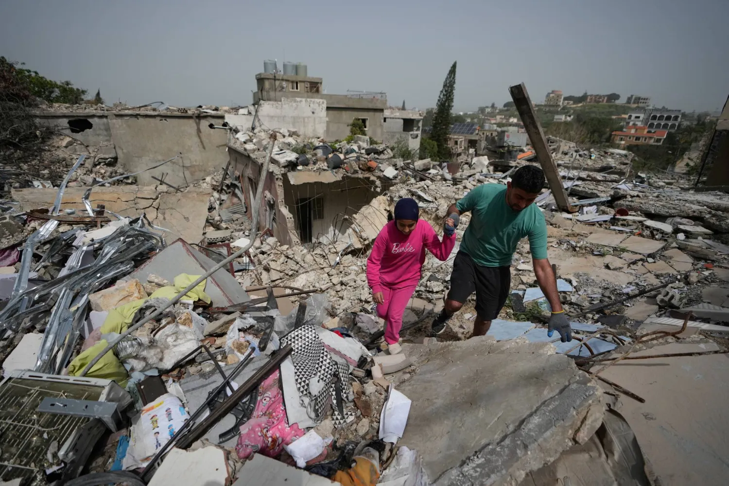 Residents walk on the rubble of destroyed houses on the second day of a ceasefire between Hezbollah and Israel in Jibchit village, south Lebanon, Saturday, April 18, 2026.(AP Photo/Mohammed Zaatari)