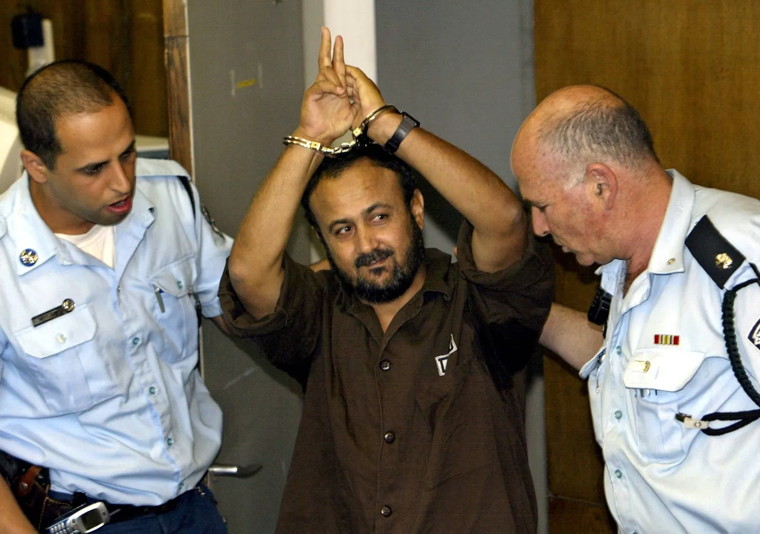 Marwan Barghouti waves as Israeli police bring him to court for a sentencing hearing in Tel Aviv, May 20, 2004. (Reuters)