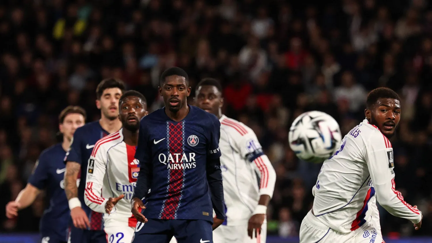 مهاجم باريس سان جيرمان عثمان ديمبيلي ومدافع أولمبيك ليون أينسلي ميتلاند نايلز يتابعان الكرة (أ.ف.ب)