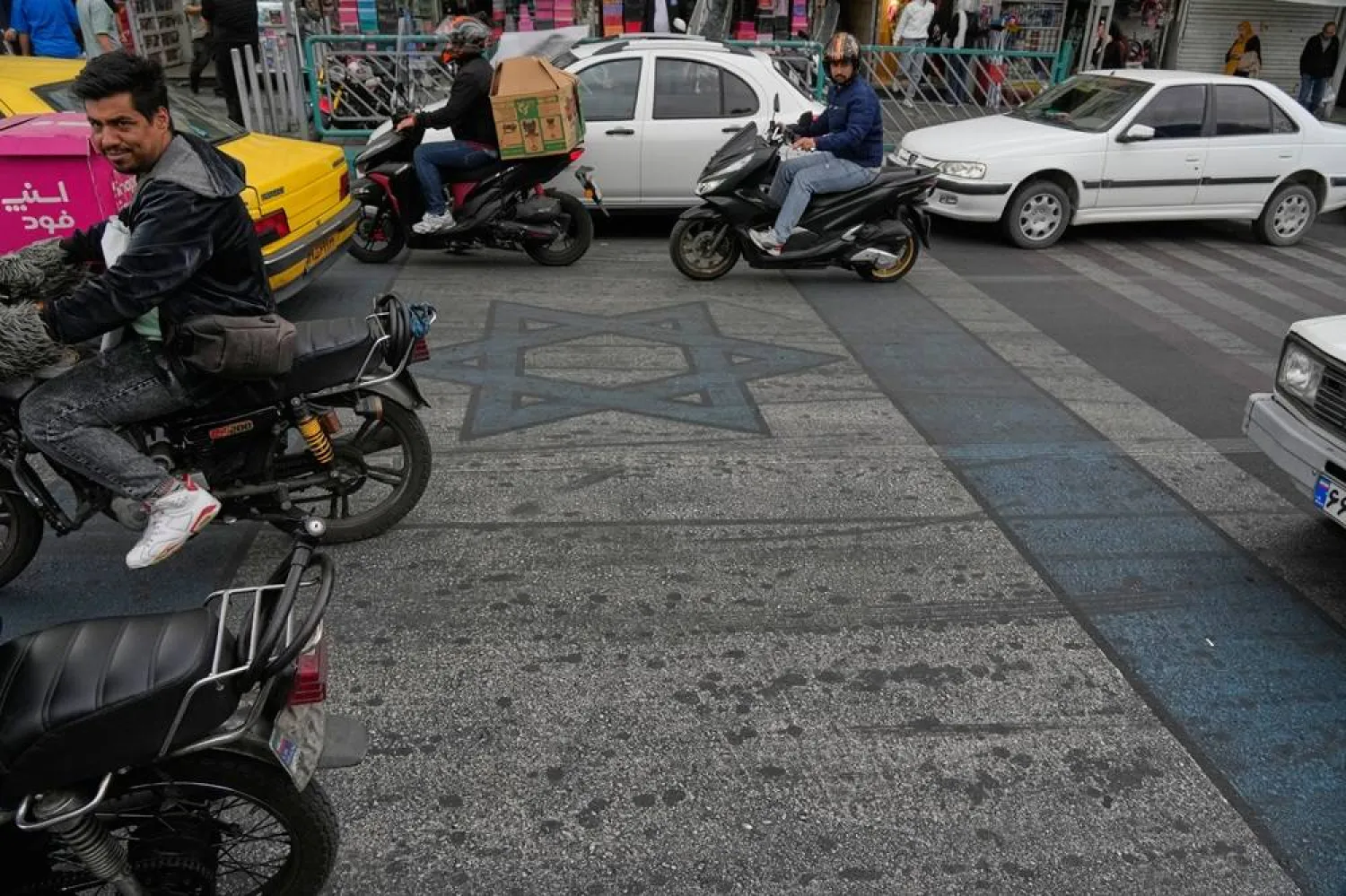  Vehicles drive on an image of the Israeli flag painted on the ground in downtown Tehran, Iran, Sunday, April 19, 2026. (AP) 