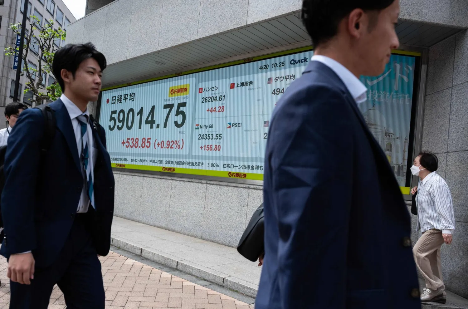 مشاة يمرون أمام شاشة تعرض حركة الأسهم في وسط طوكيو (أ.ف.ب)