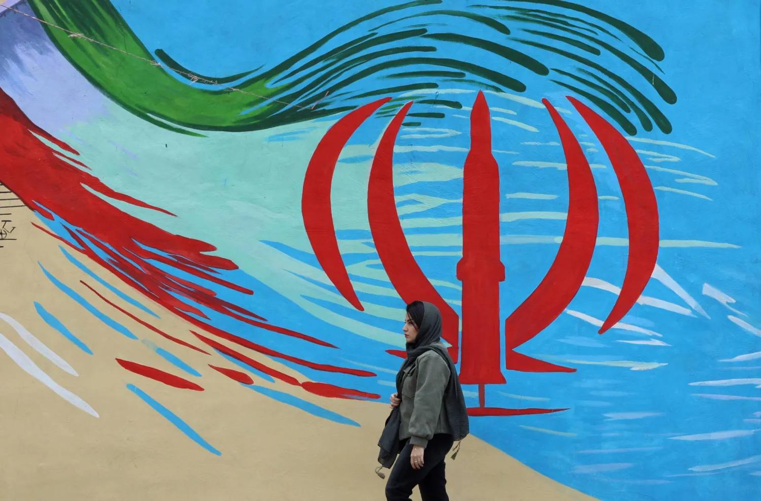 An Iranian woman walks next to a wall painting of Iran’s national flag on a street in Tehran, Iran, 20 April 2026. (EPA)