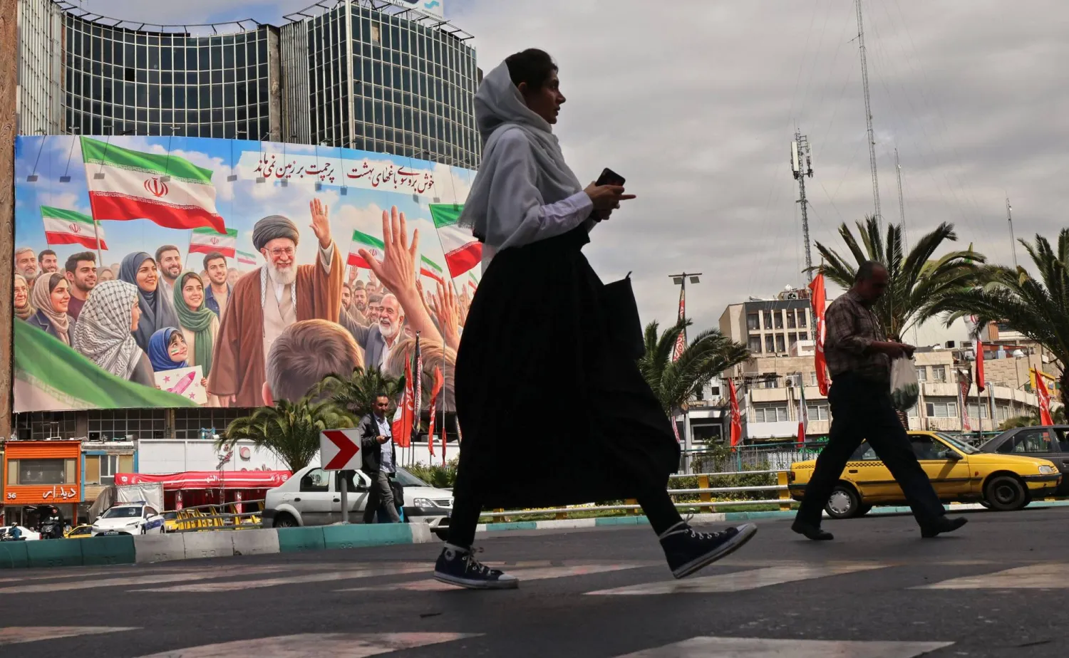 Commuters make their way past a giant billboard of slain Iranian supreme leader Ali Khamenei at the Valiasr Square in Tehran on April 19, 2026. (AFP)