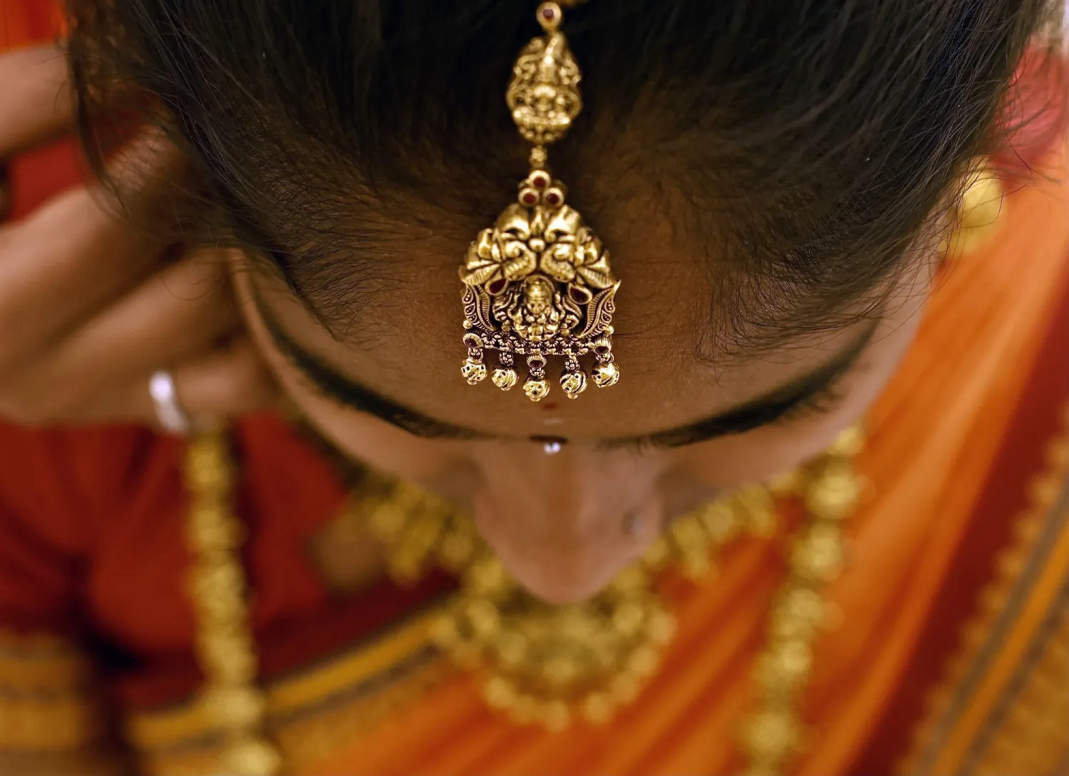 هندية ترتدي قطعة من الحُلي الذهبية داخل متجر مجوهرات في بنغالور (إ.ب.أ)