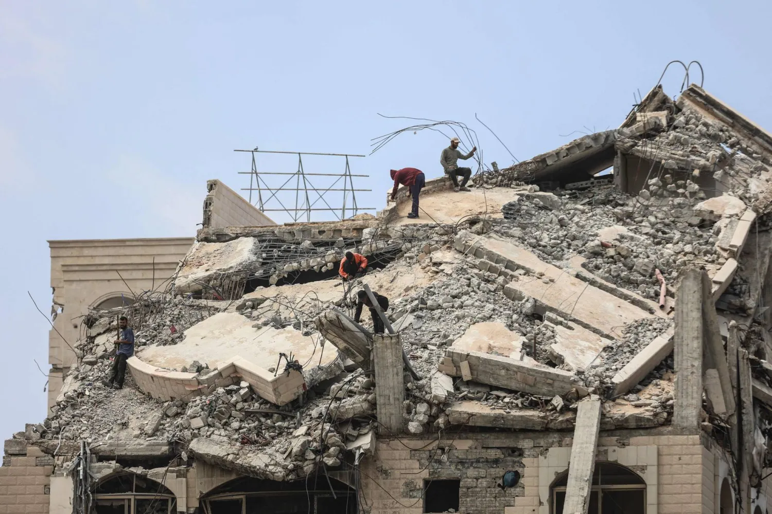 Palestinian men stand atop a heavily damaged building in Gaza City on April 20, 2026. (AFP)