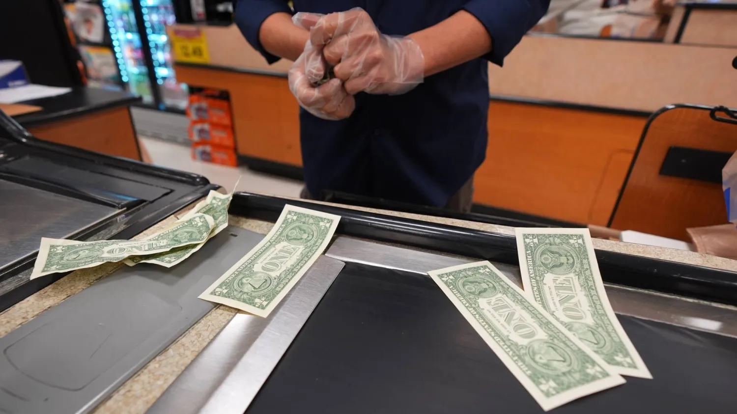 أمين صندوق في متجر بقالة يسحب أوراقاً نقدية من فئة الدولار (أ.ب)