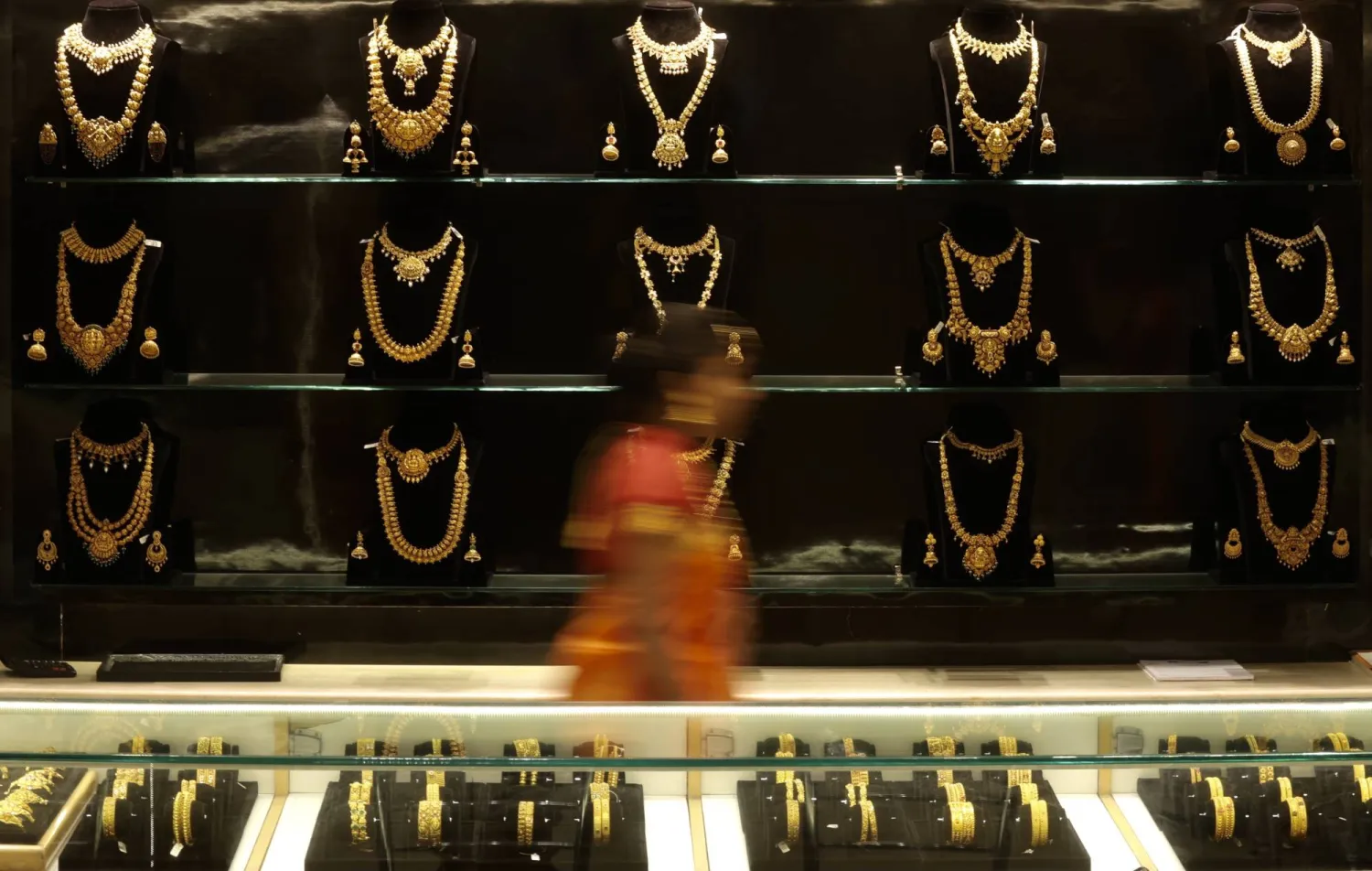 An image taken with a slow shutter speed showing an Indian woman walking in front of gold ornaments at a jewelry shop on the occasion of the Akshaya Tritiya festivities in Bangalore, India, 20 April 2026. (EPA)
