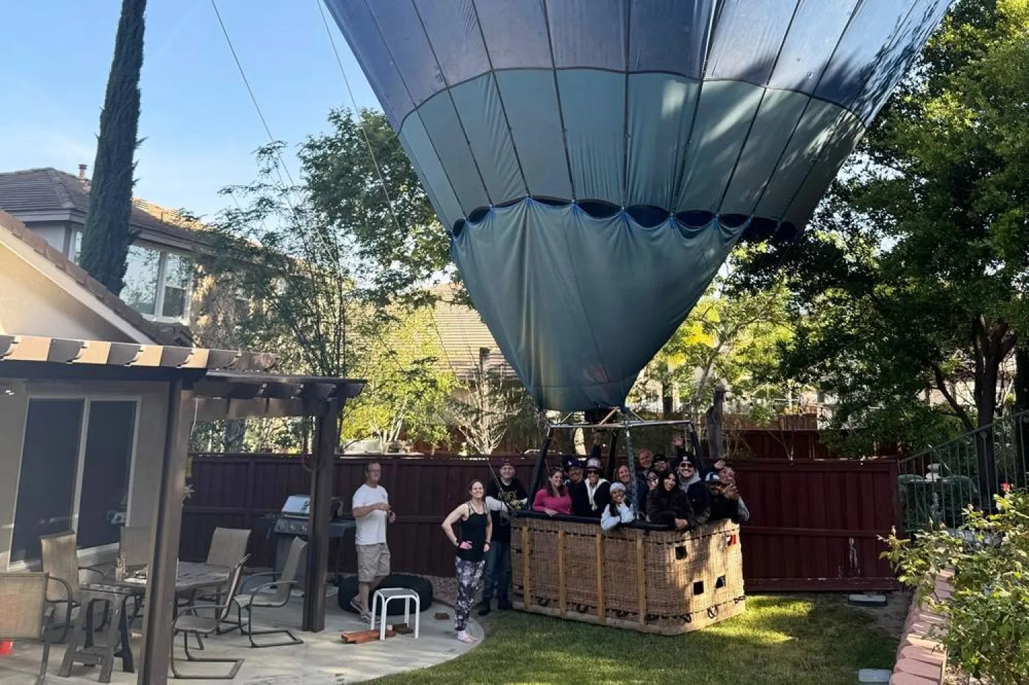 This photo provided by Hunter Perrin shows people riding a hot air balloon posing for a photo after making an emergency landing in Perrin's backyard on Saturday, April 18, 2026, in Temecula, Calif. (Hunter Perrin via AP) 