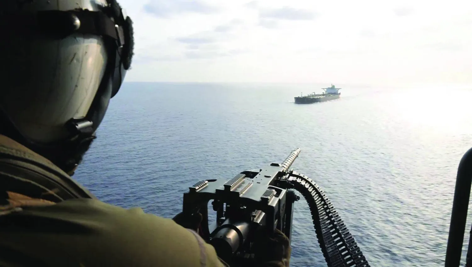 لقطة من فيديو لجندي أميركي على متن مروحية وهو يوجه تحذيراً إلى سفينة إيرانية قرب مضيق هرمز أمس (سنتكوم)