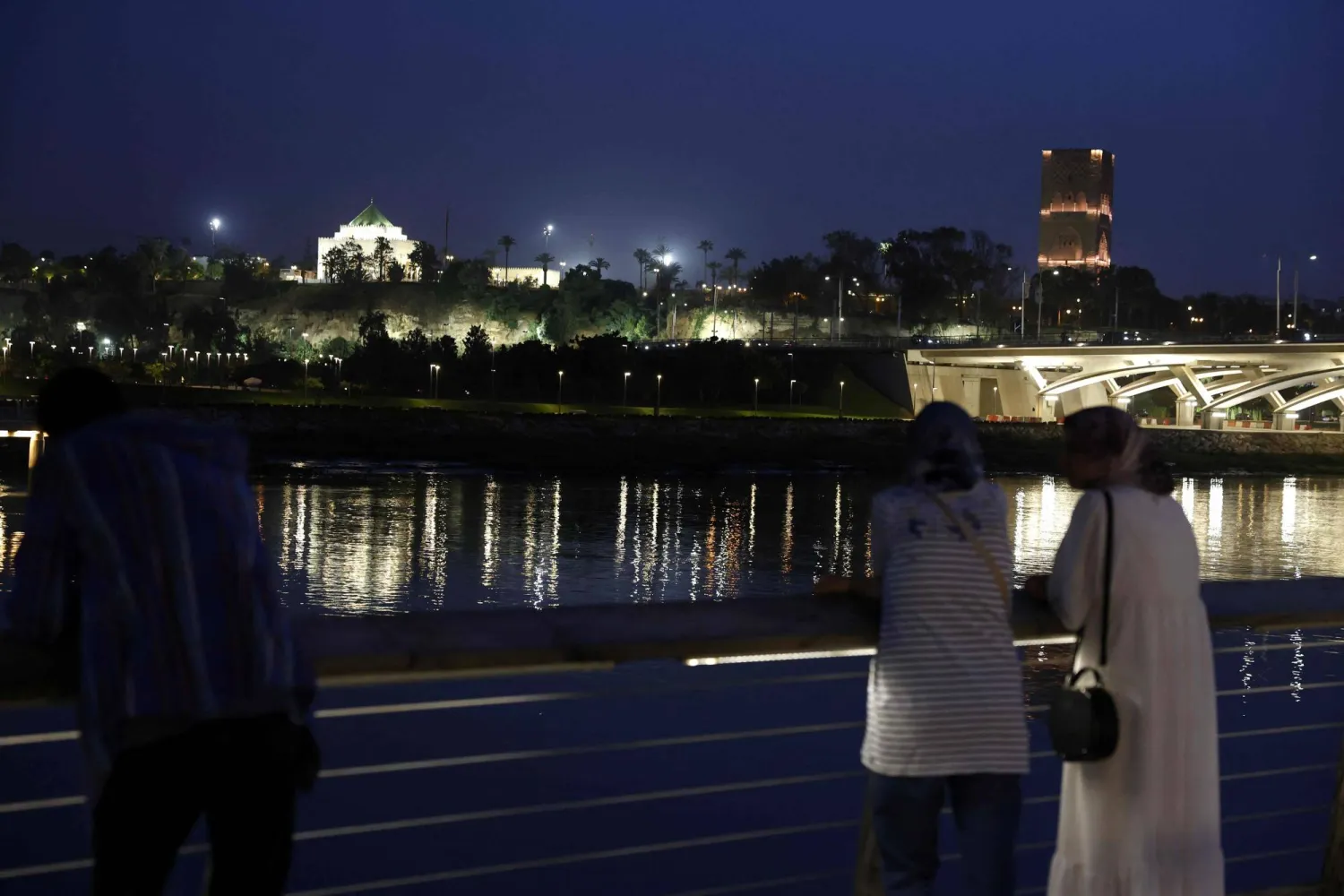  People stand looking across the river at the skyline in the coastal city of Rabat on April 20, 2026. (AFP) 