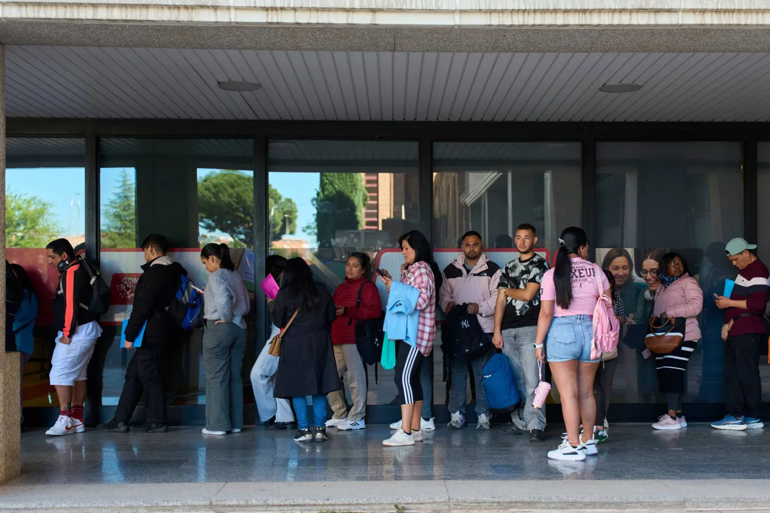 يصطف المهاجرون في طوابير للحصول على شهادة النقل العام التي ستسمح لهم بطلب الحصول على تصاريح عمل وإقامة سريعة بالعاصمة الإسبانية مدريد (أ.ب)