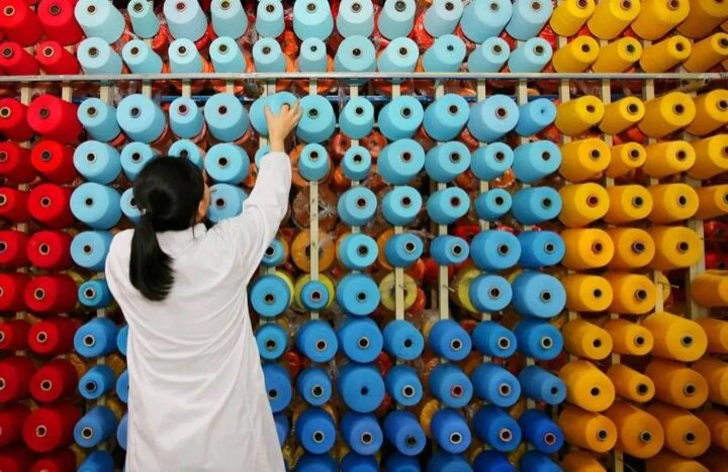 A worker arranges spools of thread at a textile factory in Haiyan, Jiangsu province, China (Reuters)