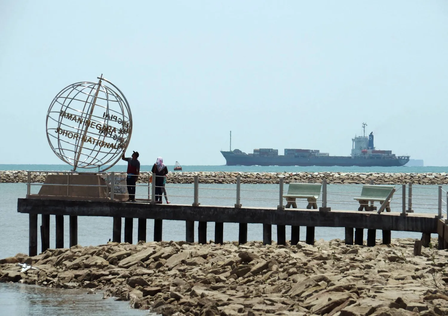 FILE PHOTO: A container ship enters the Singapore Strait for the Strait of Malacca, as tourists stand at mainland Asia's southern most point in Johor, Malaysia November 12, 2016. Picture taken November 12, 2016.  REUTERS/Henning Gloystein/File Photo