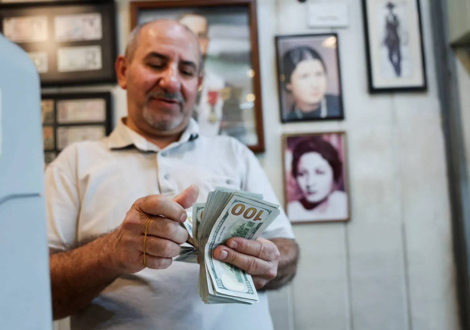 عامل يعدّ أوراقاً نقدية من فئة الدولار داخل محل صرافة ببغداد (أ.ف.ب)