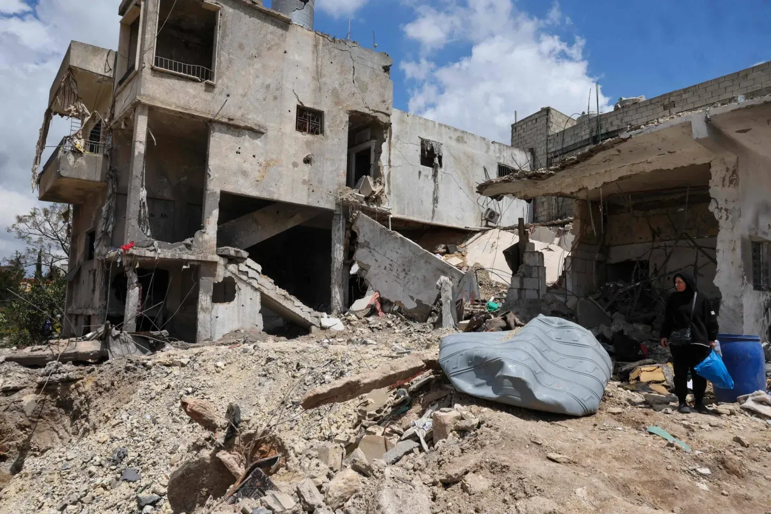 İsrail'in Lübnan'ın güneyinde düzenlediği saldırının yol açtığı yıkımın ortasında bir kadın kişisel eşyalarını taşıyor (AFP).