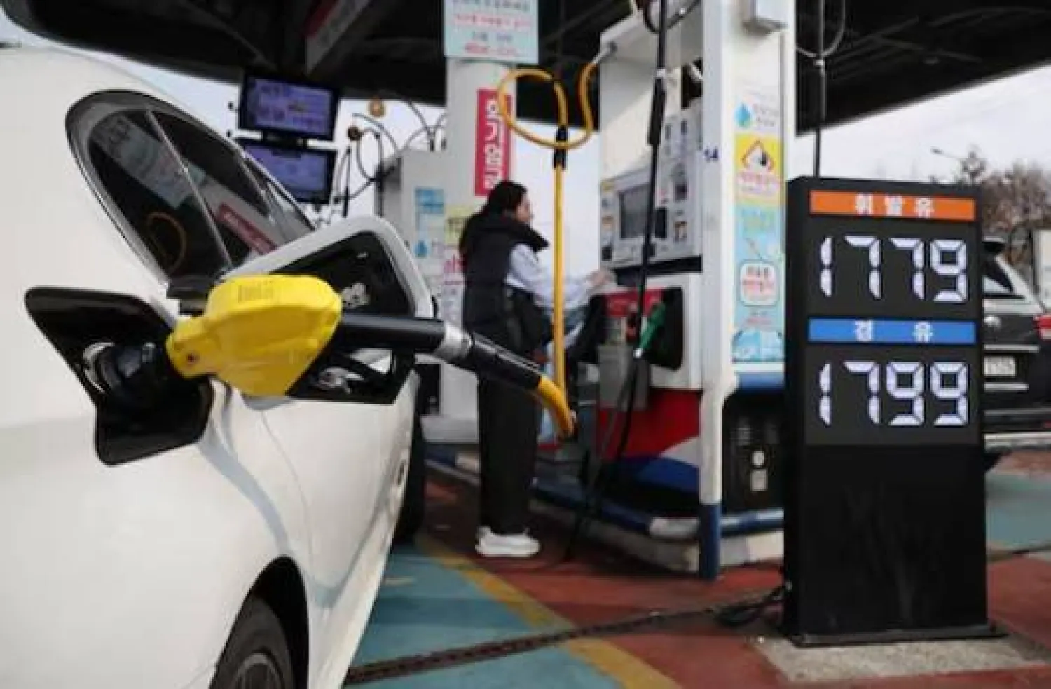 امرأة تملأ سيارتها بالنزين داخل محطة وقود في سيول (رويترز)