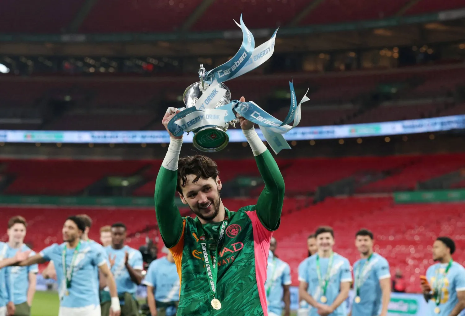 حارس مرمى مان سيتي جيمس ترافورد يحمل كأس الرابطة الإنجليزية (رويترز)