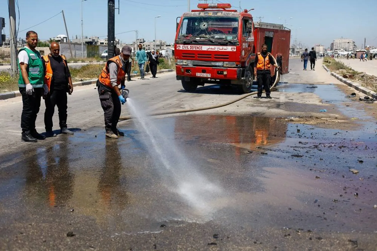  Members of civil defense personnel use a fire hose at the site of an Israeli airstrike on a car in the central Gaza Strip, April 23, 2026. (Reuters)