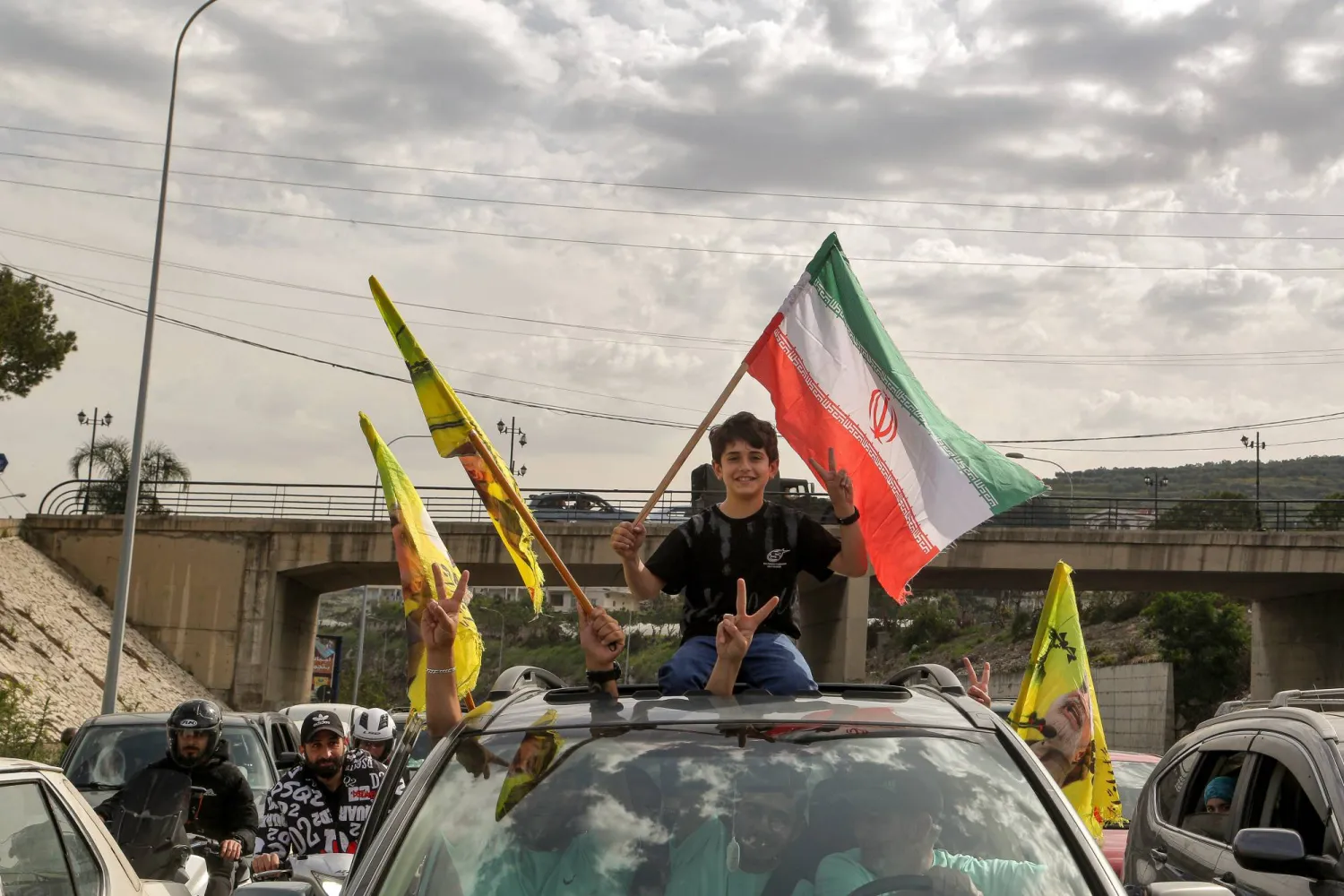 عائلة نازحة في طريق عودتها إلى الجنوب وأطفالها يرفعون أعلام إيران و«حزب الله» (د.ب.أ)