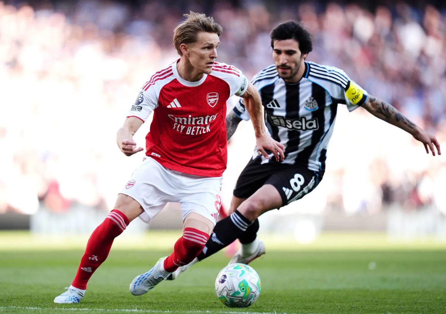 لاعب آرسنال مارتن أوديغارد يصارع على الكرة مع لاعب نيوكاسل يونايتد ساندرو تونالي (د.ب.أ)