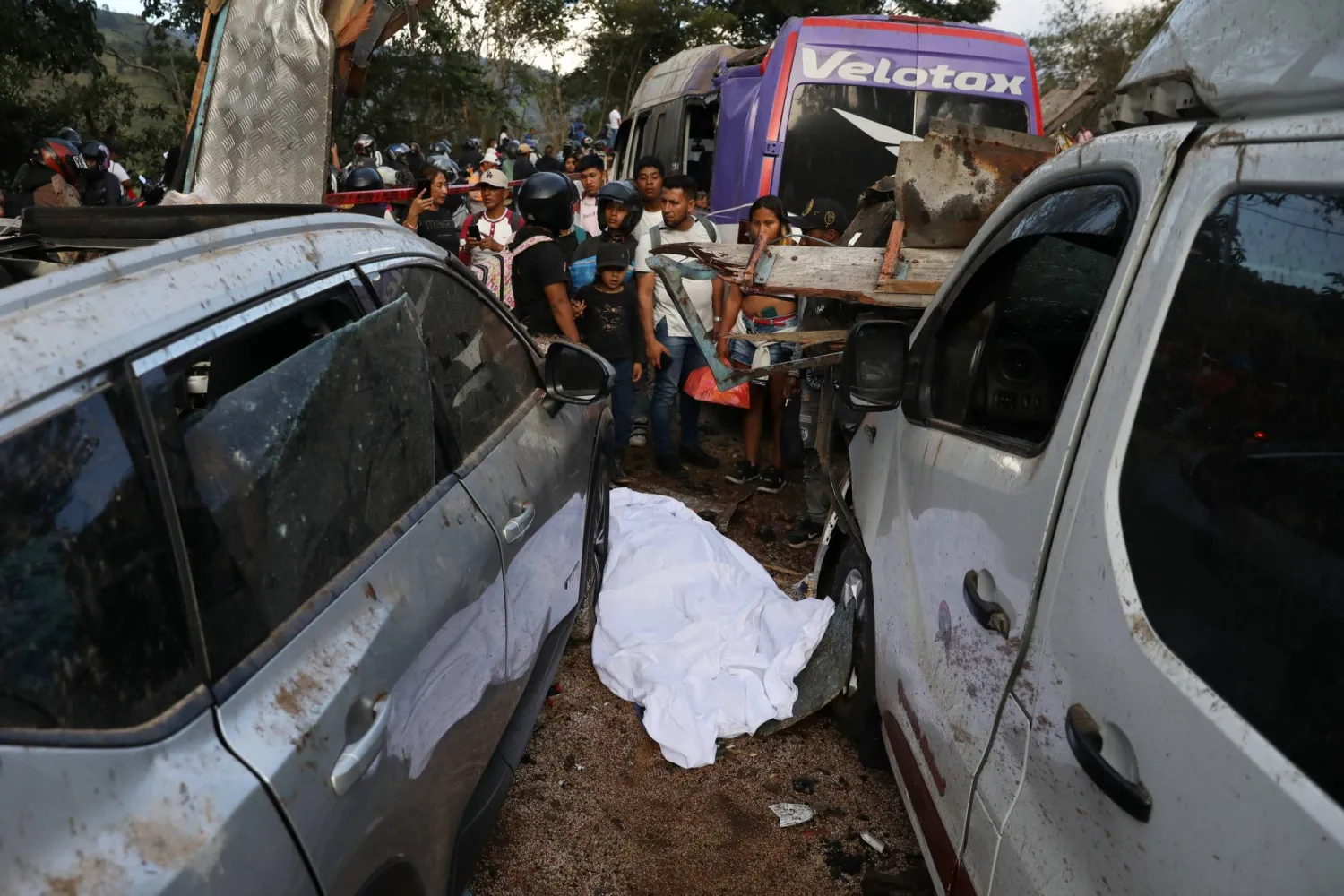 The covered body of a victim lies among vehicles damaged in an attack on the Pan-American Highway in Cajibio, Colombia, Saturday, April 25, 2026. (AP Photo/Santiago Saldarriaga)