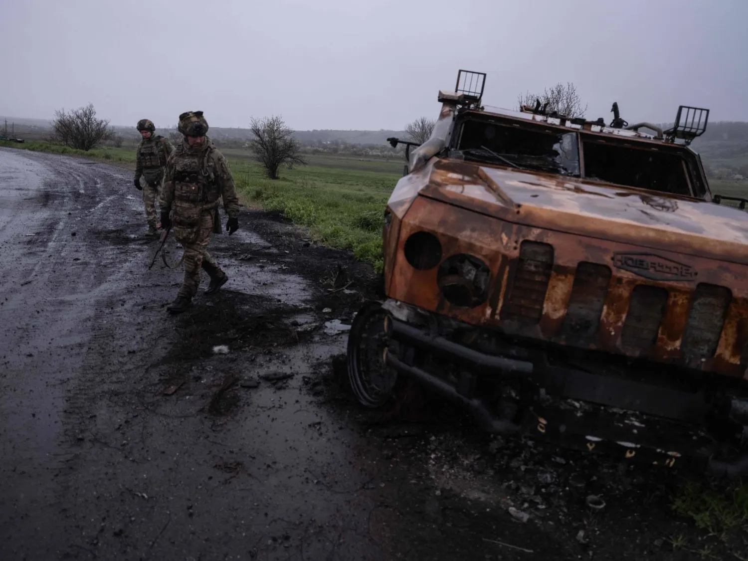 In this handout photograph taken on April 24, 2026 and released on April 25, 2026 by the press service of the 93rd Kholodnyi Yar Separate Mechanized Brigade of the Ukrainian Ground Forces, Ukrainian servicemen walk on a road past a destroyed military vehicle, near Druzhkivka, in Donetsk region, amid the Russian invasion of Ukraine. (Photo by IRYNA RYBAKOVA / The 93rd Kholodnyi Yar Separate / AFP) 