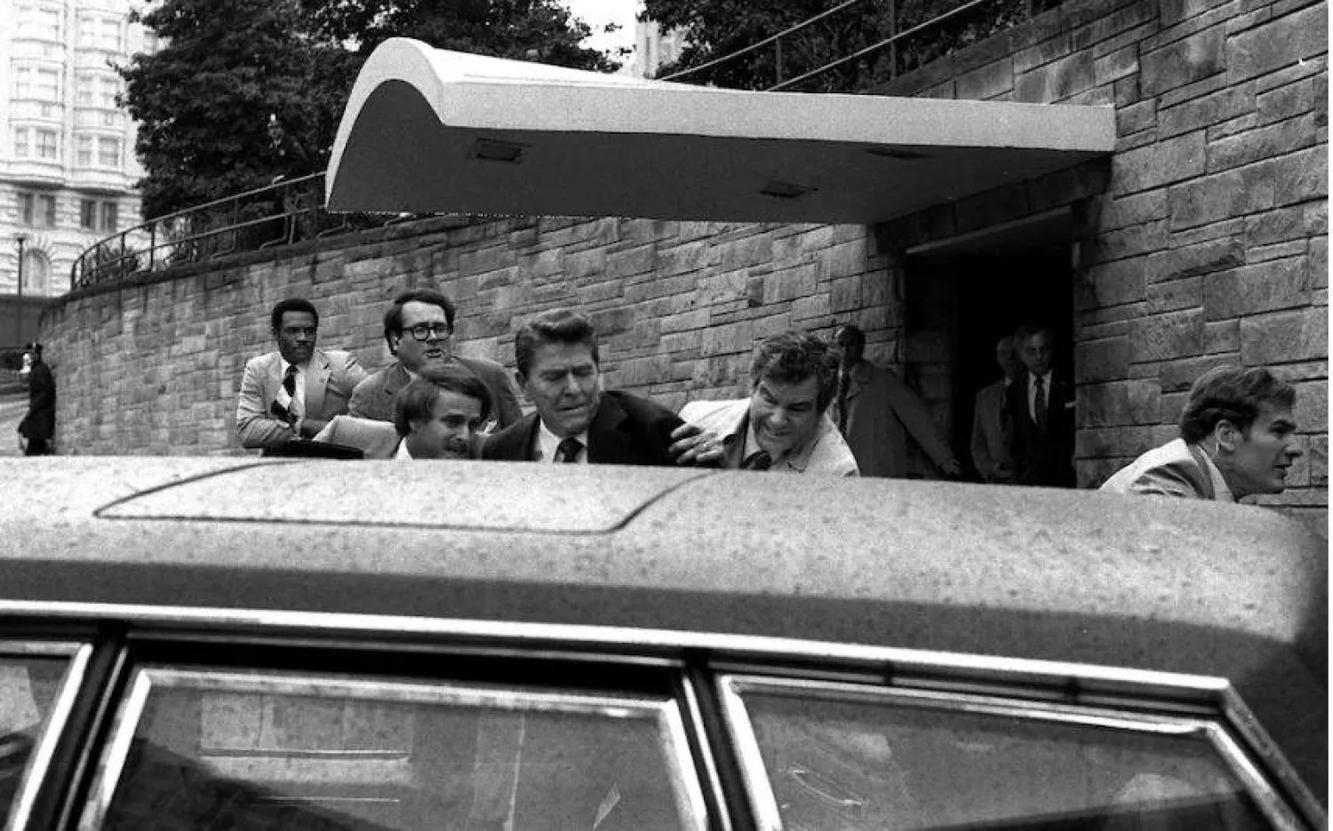 رونالد ريغان يُدفَع إلى سيارة من قبل الأمن بعد محاولة اغتياله عام 1981 (أ.ب)