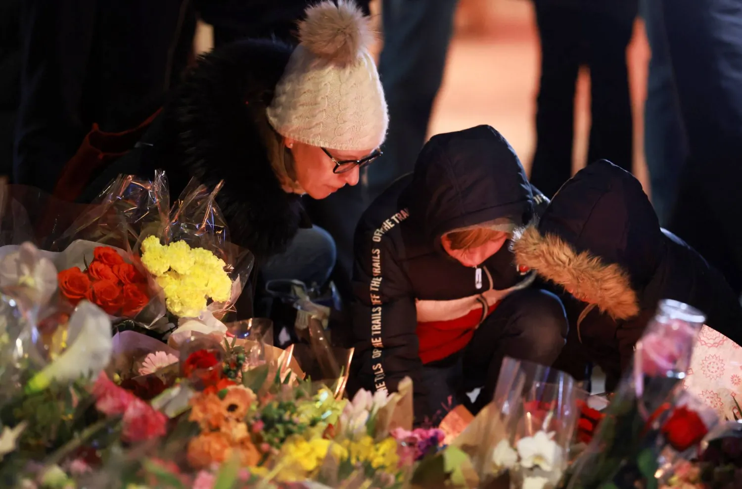 سويسريون يشعلون الشموع أمام حانة في منتجع تزلج سويسري اشتعلت بها النيران ليلة رأس السنة (رويترز)