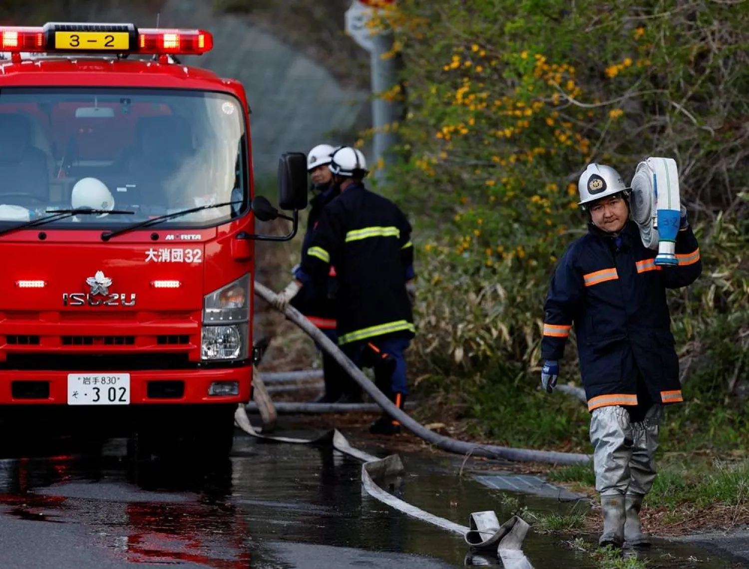 Volunteer firefighter Ryota Haga carries a fire hose to battle a wildfire in Otsuchi, Iwate Prefecture, Japan, April 26, 2026. (Reuters) 